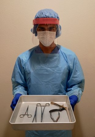 Sterile Processing Technician holding a tray full of instruments in full scrubs. Technician preparing for certification while performing hands on training. 